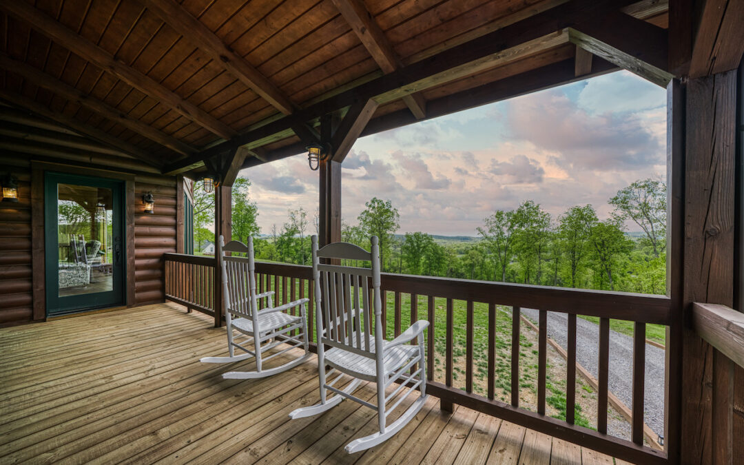 Photo of wood outdoor living space with round log house walls and wood exposed wood ceiling. The porch is rustic wood floor