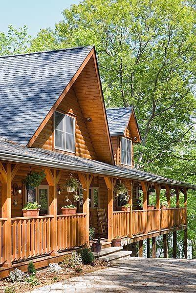 Photo of exterior of a lake home with large wrap around porch for the entry and overlooking the embankment of the lake