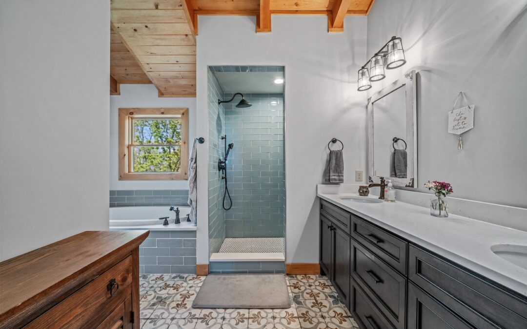 Photo of log home bathroom with wood exposed ceiling, tiled walk in shower and soaker tub