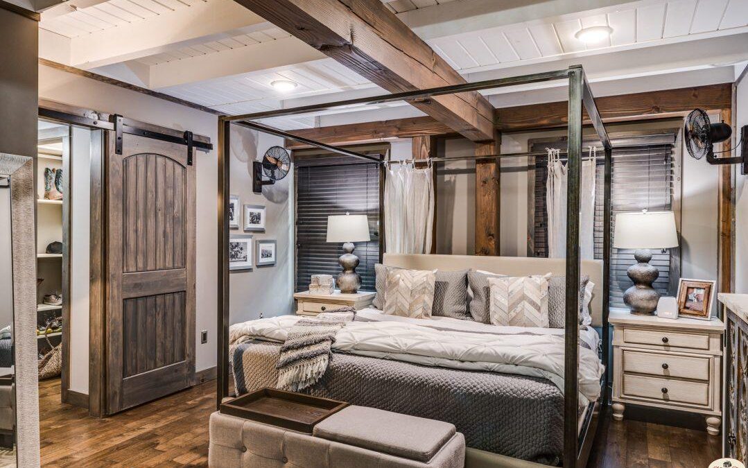 Photo of master bedroom with whitewashed wood ceiling, exposed wood floors and barn doors leading to master closet