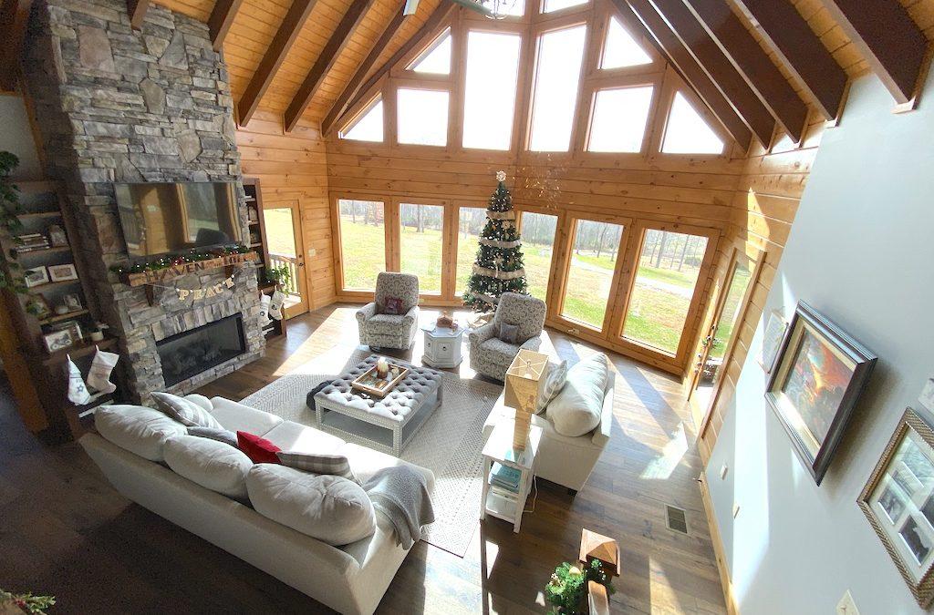 living room with christmas tree in front of large windows in a log homes